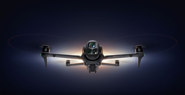 정면에서 바라본 DJI Mavic 4 Pro 드론이 어두운 배경 속에서 빛을 받으며 비행 중인 모습.