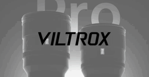 두 개의 실루엣 형태의 Viltrox Pro 시리즈 렌즈가 어두운 배경 위에 조명 효과와 함께 등장하고 있으며, 중앙에는 VILTROX 로고가 크게 표시되어 있는 티저 스타일의 이미지