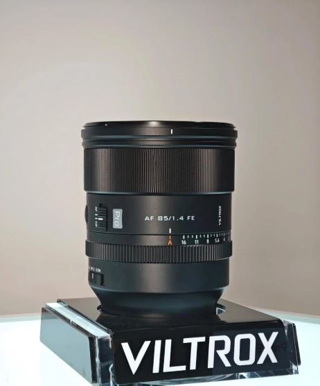 투명 아크릴 스탠드 위에 전시된 Viltrox AF 85mm f/1.4 FE Pro 렌즈. 렌즈에는 초점 조절링과 조리개 링, AF/MF 전환 스위치, Pro 시리즈 로고가 선명하게 보이며, 아래쪽 스탠드에는 VILTROX 로고가 인쇄되어 있음