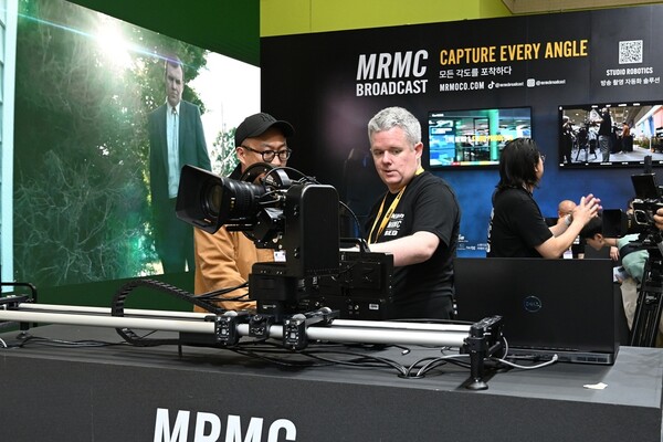 MRMC 로봇 카메라 시스템을 조작하고 있는 해외 기술 담당자와 방문객