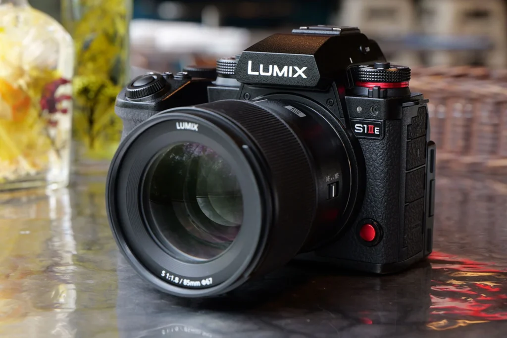 Panasonic Lumix S1 IIE 카메라에 85mm 렌즈가 장착된 상태로, 실내 테이블 위에 놓여 있는 모습.