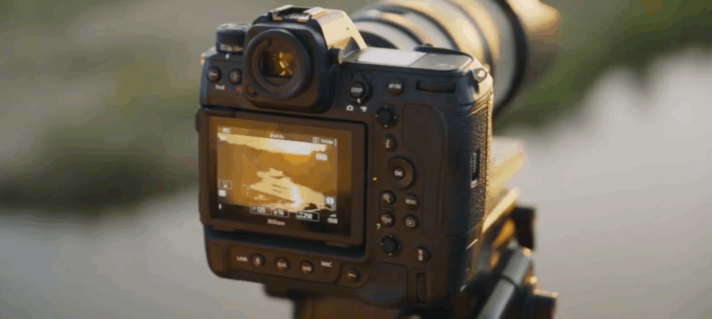 삼각대에 장착된 Nikon Z9 II 카메라의 후면이 보이며, LCD 화면에는 석양이 비치는 강가 풍경이 촬영되고 있는 모습이 표시되어 있다.