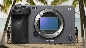 Sony FX2 또는 유사한 시네마 스타일 풀프레임 카메라가 야자수가 있는 해변 배경 앞에 배치되어 있으며, 촬영 현장의 모습이 흐리게 보인다.