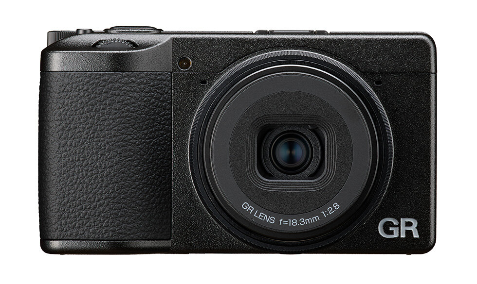 리코 GR IV 카메라 정면 이미지. 18.3mm f/2.8 GR 렌즈가 탑재되어 있으며, 검정색 본체와 컴팩트한 디자인이 특징이다.
