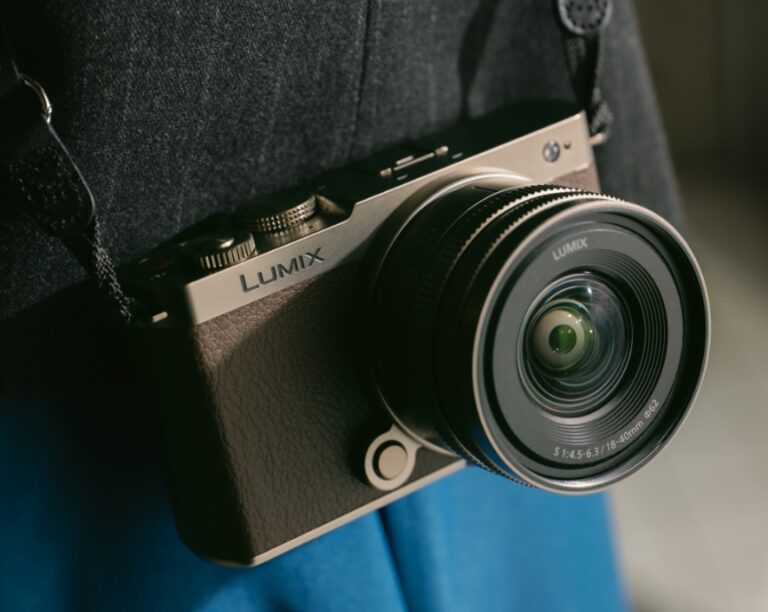 Panasonic Lumix S9 Titanium Gold 에디션이 사용자의 몸에 스트랩으로 걸려 있는 모습. 가죽 질감의 브라운 바디와 금속 광택의 상단부가 조화를 이루며 프리미엄 디자인이 돋보인다.