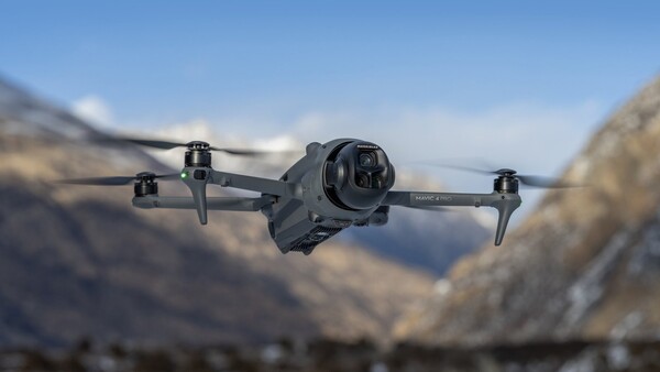 설산을 배경으로 공중을 비행 중인 DJI Mavic 4 Pro 드론. 날개를 펼친 상태에서 전면 고화질 카메라가 중앙에 강조되며, 자연 환경 속 안정적인 비행을 연출.