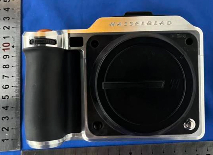 FCC 인증 문서를 통해 유출된 Hasselblad X2DII의 전면 이미지. 전면 디자인은 금속 프레임 위에 대형 센서 마운트와 블랙 러버 그립이 장착되어 있으며, 상단에는 ‘HASSELBLAD’ 로고가 각인되어 있다. 카메라 외관은 측정용 자와 함께 배치되어 크기 추정이 가능하다.