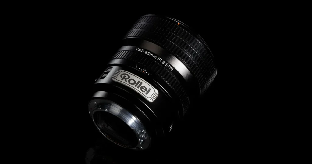검은 배경에서 조명을 받은 Rollei AF 85mm f/1.8 STM 렌즈, 렌즈 마운트와 Rollei 로고가 보이는 뒷면 강조 이미지