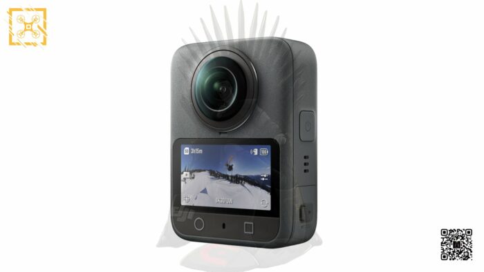 DJI 오즈모 360 카메라의 3/4 측면 각도 이미지입니다. 카메라는 정사각형에 가까운 형태로, 전면과 후면에 렌즈가 각각 하나씩 있습니다. 전면에는 작은 디스플레이가 켜져 있어 스키를 타는 사람의 모습이 360도 영상으로 보이며, 배터리 잔량, 녹화 시간 등의 정보가 표시되어 있습니다. 측면에는 전원 버튼과 기타 컨트롤 버튼이 보이고, 상단에는 미세한 돌기 패턴이 있습니다.