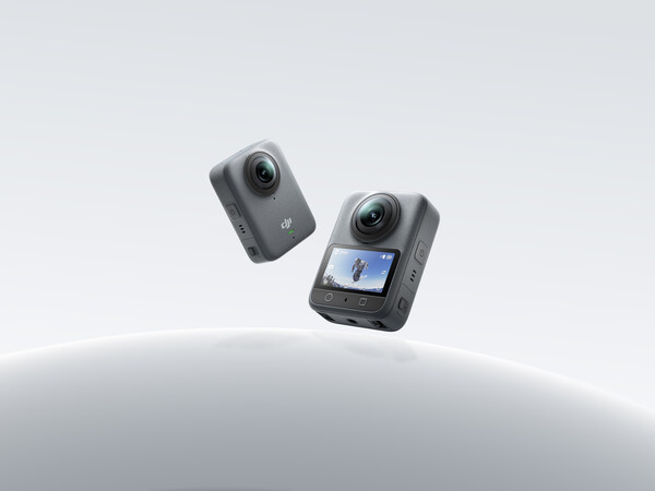 공중에 떠 있는 DJI Osmo 360 카메라 두 대. 한쪽은 후면 디스플레이를 통해 화면을 보여주고 있으며, 1인치 듀얼 렌즈가 장착된 회색 본체가 강조되고 있다.