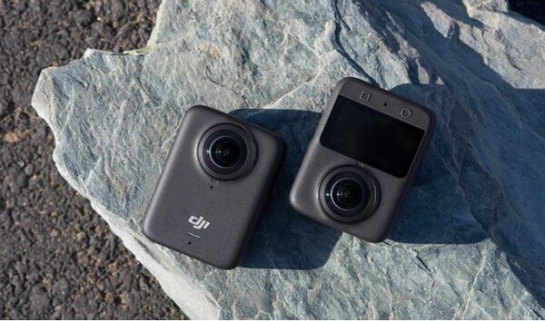 "야외 바위 위에 놓여 있는 DJI의 360도 액션 카메라 Osmo 360. 하나는 전면 렌즈가 보이고, 다른 하나는 후면 디스플레이와 함께 듀얼 렌즈가 탑재된 모습이 확인된다."