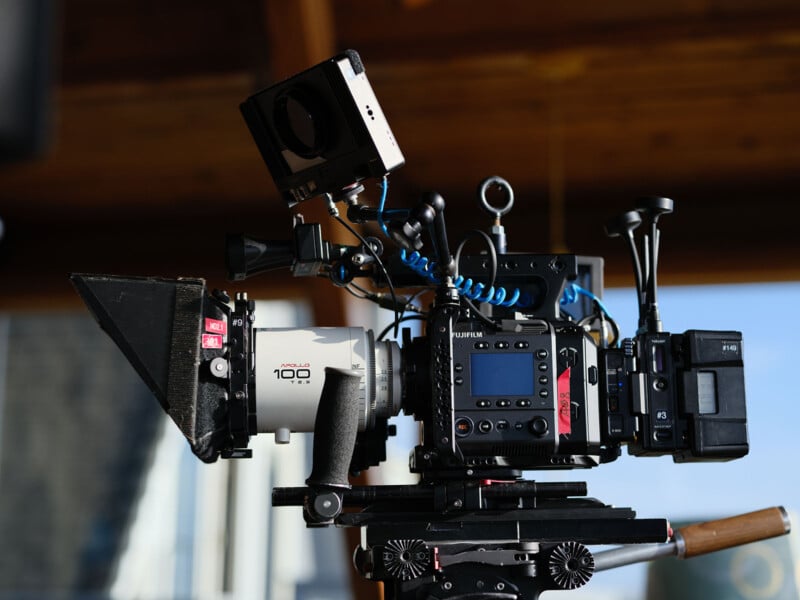 Fujifilm GFX Eterna 55 digital cinema camera rig mounted on a tripod, equipped with a cinema lens, matte box, monitor, and multiple accessories, set up indoors with natural light.