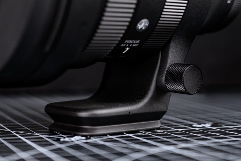 Sigma 135mm f/1.4 DG Art 렌즈 삼각대 마운트 클로즈업, 금속 노브와 초점 전환 스위치가 보이는 디테일