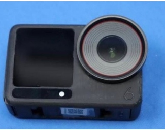 렌즈 주변에 붉은 테두리가 있는 블랙 바디의 DJI Osmo Action 6 카메라. 전면에 작은 디스플레이와 렌즈가 함께 배치되어 있으며, 좌측 하단에는 숫자 ‘6’이 표시되어 있다.