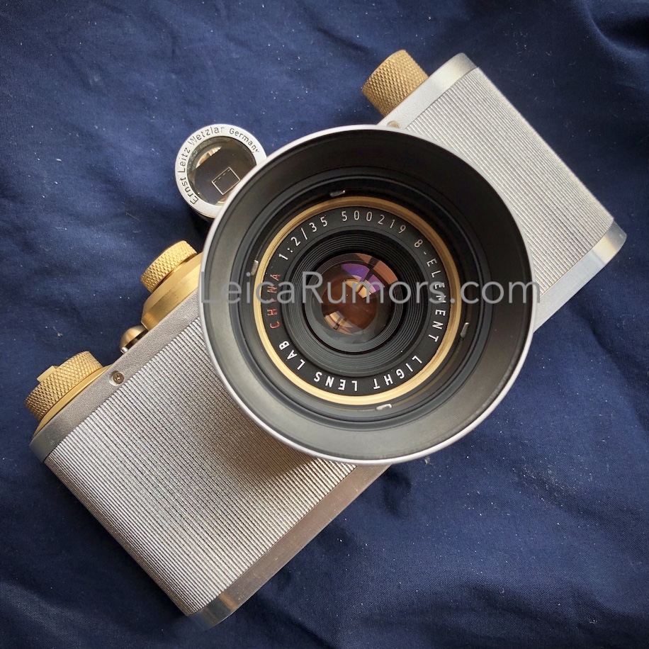 Light Lens Lab 렌즈가 장착된 바르낙 스타일 필름 카메라의 전면 모습. 황동 조작 다이얼과 은색 본체가 돋보이며, 렌즈 전면에는 “Light Lens Lab 35mm f/2” 표기가 보인다.